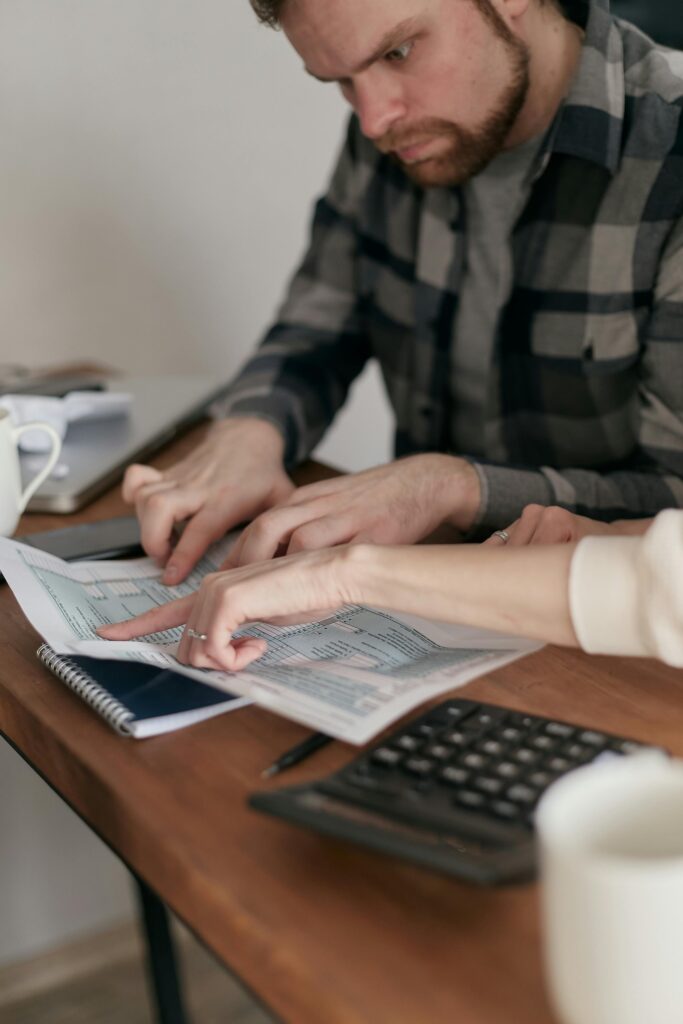 A couple discussing financial papers at their home table with a calculator.